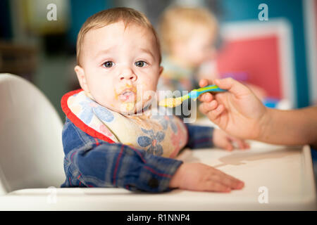 Un bambino bambino mangia il cibo con il cucchiaio di madre Foto Stock