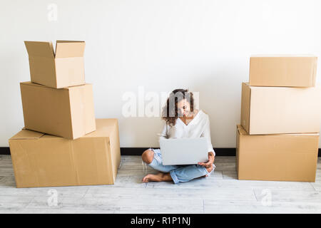 Casa in movimento concetto - Excited donna rilassante sul piano ricerca sul computer e celebrare nella nuova casa. razza mista asiatica modello cinese. Foto Stock