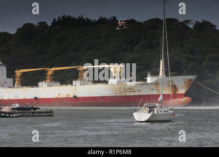 Elicottero guardia costiera passando al di sopra della cisterna e un elicottero membro di equipaggio essendo winched giù per aiutare la vittima. Fiume Fal, Cornwall. Foto Stock