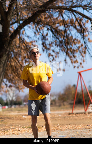 Senior uomo giocare a basket nel parco Foto Stock