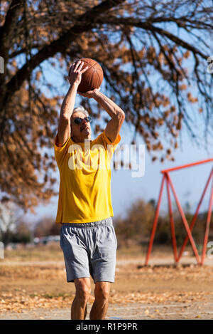Senior uomo giocare a basket nel parco Foto Stock