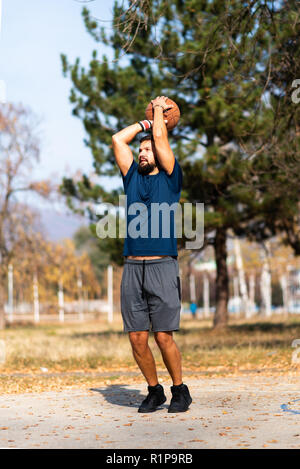 L'uomo giocare a basket nel parco vicino fino Foto Stock