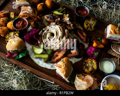 Antipasto piatto freddo piatto a base di carne con prosciutto, fette di prosciutto crudo, Beef Jerky, salame e rucola sul bordo di taglio su sfondo di legno vicino. App di carne Foto Stock