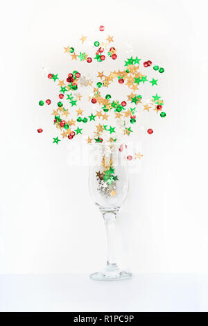 Coriandoli colorate a forma di stelle effuso bicchieri di champagne su bianco. Vista dall'alto. Festa di Natale. Notte magica. Foto Stock