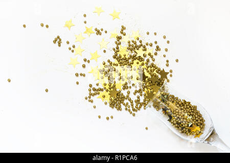 Golden coriandoli a forma di stelle effuso bicchieri di champagne su bianco. Vista dall'alto. Festa di Natale. Notte magica. Foto Stock