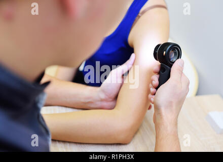 Medico dermatologo esamina la pelle della ragazza del paziente per la presenza di moli, birthmarks, tumori. Dermatoscopy, prevenzione del melanoma, pelle Foto Stock