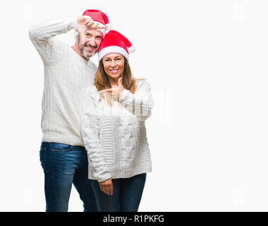 Centro Ispanico di età matura con cappello a Natale su sfondo isolato sorridente rendendo il telaio con le mani e le dita con la faccia felice. Creatività e Foto Stock