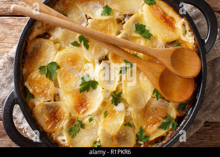 Janssonin Kiusaus patate al forno con i filetti di acciuga, cipolle e panna in una padella sul tavolo. parte superiore orizzontale vista da sopra. Pinna Foto Stock