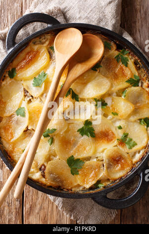 Janssonin Kiusaus patate al forno con i filetti di acciuga, cipolle e panna in una padella sul tavolo. Verticale in alto vista da sopra. Finni Foto Stock