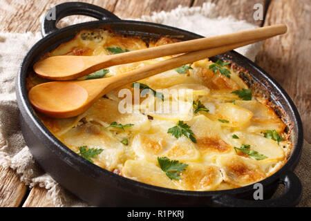 Janssonin Kiusaus patate al forno con i filetti di acciuga, cipolle e panna in una padella sul tavolo. orizzontale. Alimentare finlandese. Foto Stock