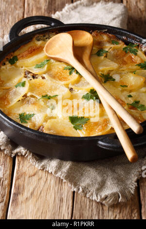 Tradizionale cibo finlandese Janssonin Kiusaus patate al forno con le acciughe, cipolle e panna in una padella sulla tavola verticale. Foto Stock