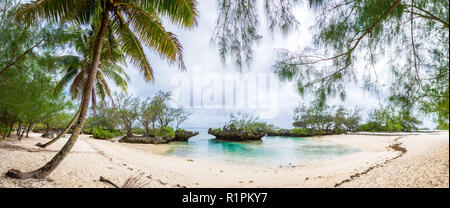 Vista di giallo sabbia bianca spiaggia tropicale sotto le palme in una baia isolata con pietre coralline. Rimatara Island Isole Australi, Polinesia francese. Foto Stock