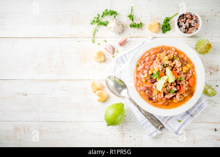 Chili con carne in piastra bianca su sfondo di legno. Peperoncino Messicano con carne, nachos, calce, peperoncino. Messico e Texas americano cibo tradizionale, t Foto Stock