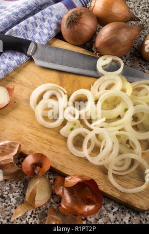 Taglio fresco di materie organiche anelli di cipolla su una tavola di legno e un coltello Foto Stock