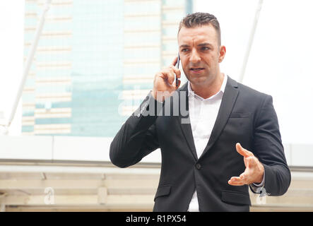 Ritratto imprenditore parlando su mobilephone con sfondo city tower Foto Stock