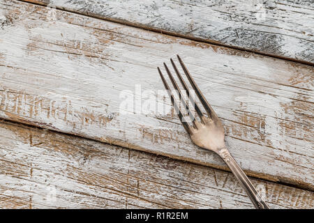 Compresse con forca d'argento su un vecchio tavolo di legno con vernice bianca Foto Stock