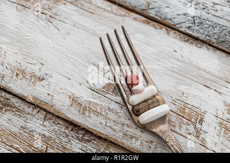 Compresse con forca d'argento su un vecchio tavolo di legno con vernice bianca Foto Stock