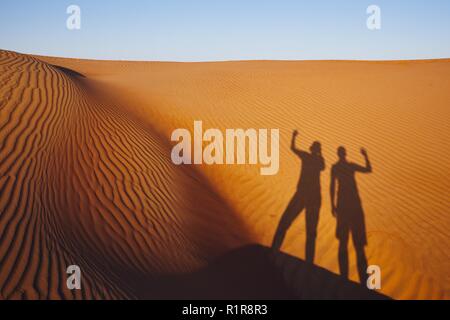 Le ombre dei due amici sventolare sul messaggio di saluto. Le dune di sabbia in Oman deserto. Foto Stock