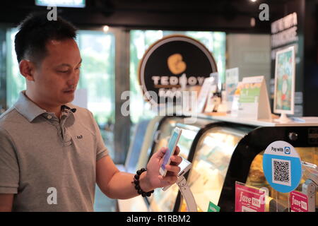 Pechino, Malaysia. 8 Ago, 2018. Un uomo paga per il caffè eseguendo la scansione del codice QR di Kuala Lumpur in Malesia, e il Agosto 8, 2018. Credito: Zhu Wei/Xinhua/Alamy Live News Foto Stock