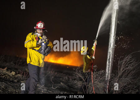 Rialto, CA, Stati Uniti d'America. Xiv Nov, 2018. Alle 9 pm, un fast-spazzola mobile incendio scoppia, bruciando 20 acri nei primi tre minuti. Vigili del fuoco spray poli elettrici evitando ulteriore scintilla ups. Credito: Chris Rusanowsky/ZUMA filo/Alamy Live News Foto Stock