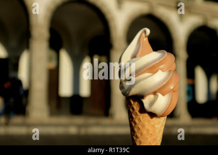 Due-tono Soft servire il gelato in cono di luce solare con sfocate edificio Vintage in background Foto Stock
