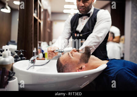 Hipster uomo client haidresser visita e un parrucchiere in un barbiere. Foto Stock