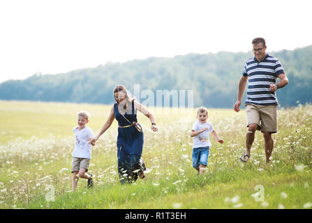 Una giovane famiglia con due figli piccoli a piedi nella natura in un giorno di estate. Foto Stock