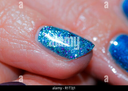 Blu scintillanti glittery unghie dopo appena essendo applicato in una manicure. Foto Stock