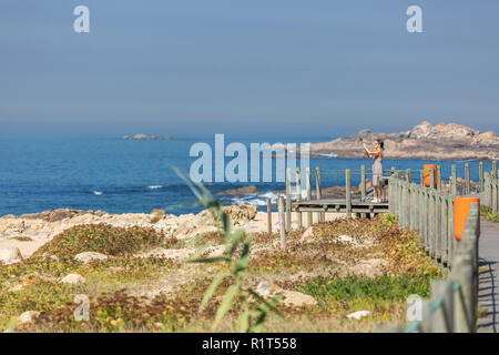 Leca da Palmeira/Porto/Portogallo - 10 04 2018: Vista della donna a scattare foto su pedonale passerella in legno, la spiaggia e il mare come sfondo, in Portogallo Foto Stock