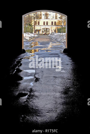 Arco in un vicolo buio con asfalto umido dopo la pioggia che cade sul luminoso Street Foto Stock