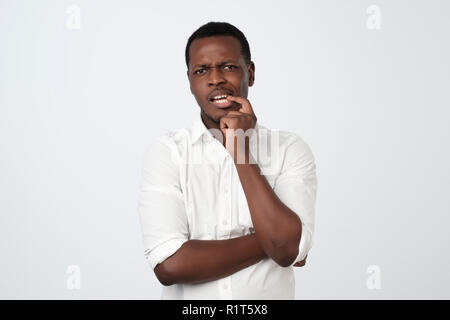 Studio shot di pensieroso grave perplesso African American uomo toccando il suo mento, guardando pensosa e scettici circa qualcosa, profondo in pensieri, hes Foto Stock