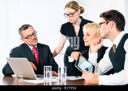 Imprenditore mostrando qualcosa ai suoi colleghi sul computer portatile Foto Stock