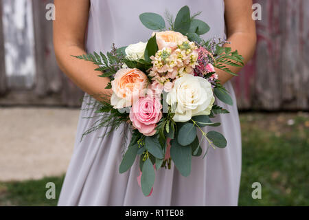 Damigella in viola tenendo un bellissimo mazzo di fiori. Foto Stock