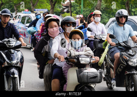 Scena di strada con persone che indossano maschere viso sulla moto e scooter per proteggere contro l'inquinamento atmosferico in una trafficata strada urbana. Hanoi, Vietnam Asia Foto Stock