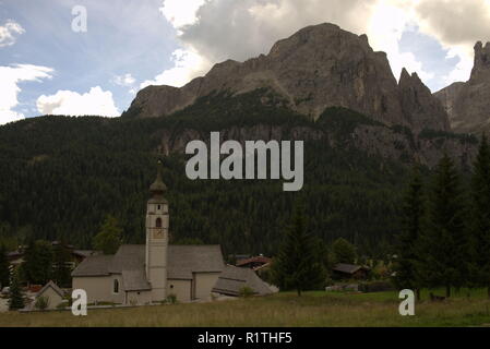 Vista verso il gruppo del Sella nelle Dolomiti italiane, davanti una tipica chiesa alpina Foto Stock