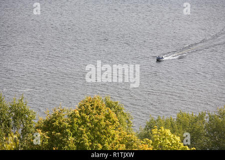 Piccola barca a vela lungo il fiume su uno sfondo di alberi. Foto Stock