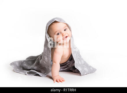 Il bambino sotto un asciugamano. Età di dieci mesi. Esso è isolato su sfondo bianco Foto Stock