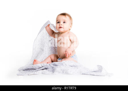 Il bambino sotto un asciugamano. Età di dieci mesi. Esso è isolato su sfondo bianco Foto Stock