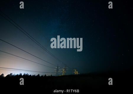 Incredibile cielo notturno con stelle, la Via Lattea che passa al di sopra della linea di alimentazione in una lunga esposizione timelapse. Bella vista panoramica. La natura in campagna. Ast Foto Stock