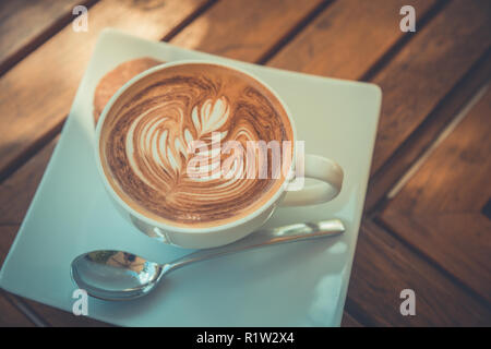 Bel mattino tavolo in legno top con caffè, latte art e cookie. Per iniziare la giornata, buon umore concetto. Foto Stock