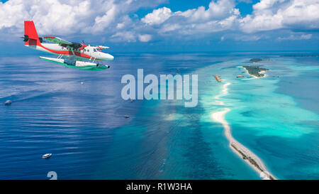 Vista aerea di un idrovolante avvicinando isola delle Maldive. Maldive spiaggia da birds eye view. Vista aerea sulle isole Maldive, atolli e mare blu Foto Stock