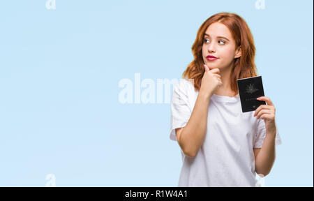 Giovane donna bellissima azienda passaporto dell Australia su sfondo isolato faccia seriamente pensando di domanda, molto confusa idea Foto Stock