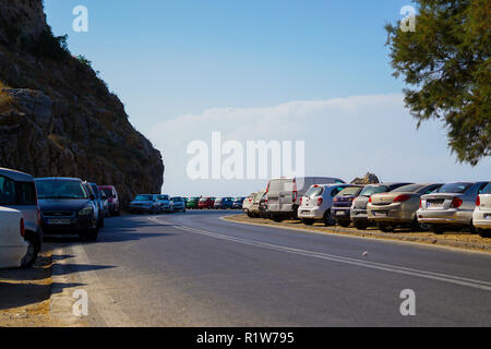 Automobili parcheggiate lungo la strada tortuosa accanto alla scogliera. Rethimno, Creta. Foto Stock