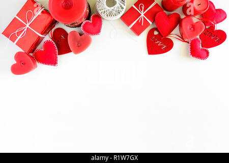 Presente box con un feltro di cuori e candele su bianco sullo sfondo di legno. Il giorno di San Valentino festa concetto. Vista dall'alto. Lay piatto. Foto Stock