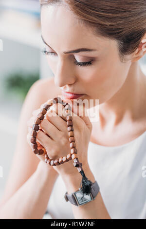 Bella donna orante con legno i grani del rosario Foto Stock