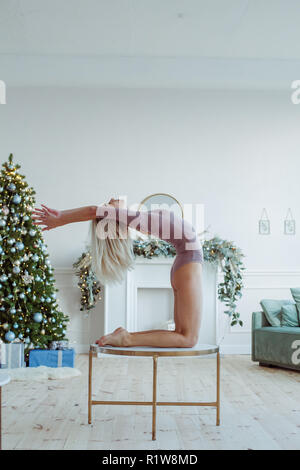 Giovane e bella donna che lavora fuori in soppalco interno, facendo esercizi yoga, stretching, stando in piedi in Ustrasana, Camel postura, a piena lunghezza e spazio di copia Foto Stock