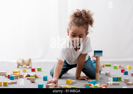 Adorable African American bambino in bianco t-shirt giocando con colorati cubetti giocattolo Foto Stock