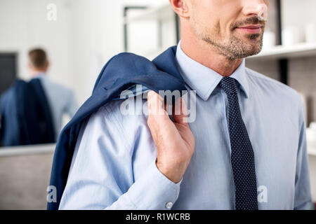 Immagine ritagliata di imprenditore in posa con la camicia sulla spalla nella stanza da bagno Foto Stock
