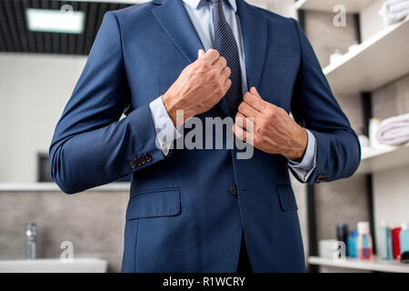 Ritagliato shot di imprenditore regolazione giacca tuta in bagno Foto Stock