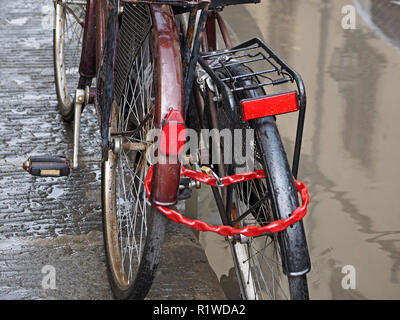 Vista ravvicinata di due vecchie biciclette parcheggiate con riflettori rossi bloccati insieme con una catena di rosso insieme in Firenze e Toscana Foto Stock